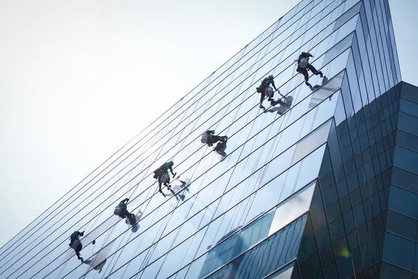 Grupo de trabalhadores serviço de limpeza de janelas em edifício alto — Fotografia de Stock