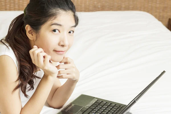 Happy young asian woman working with laptop in bedroom — Stock Photo, Image
