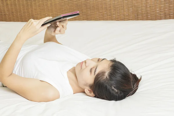 Gelukkig jonge Aziatische vrouw vast en werken op de Tablet PC in slaapkam — Stockfoto