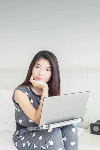 Молодая азиатка играет в интернет на ноутбуке и улыбается — стоковое фото