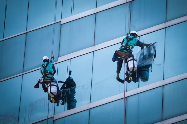 Gruppe von Arbeitern putzt Fenster an Hochhaus Stockbild