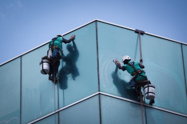 Yüksek binadaki pencereleri temizleyen bir grup işçi
