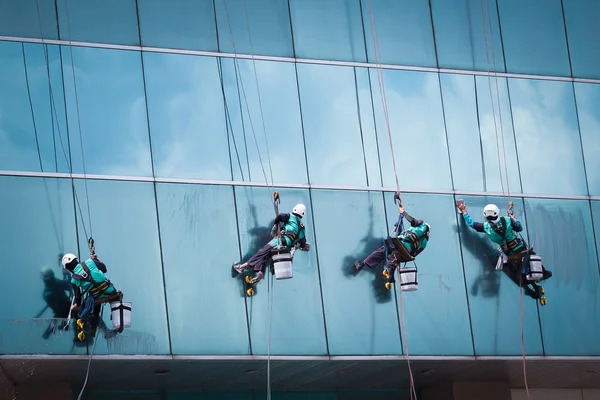 Grupo de trabalhadores serviço de limpeza de janelas em edifício alto — Fotografia de Stock