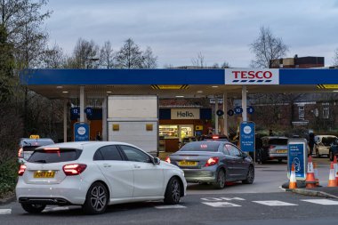 Wigan, İngiltere: 10 Mart 2022: İngiliz sürücüler panik içinde benzin alırken, Tesco benzin istasyonunda benzin almak için kuyrukta bekleyen arabalar