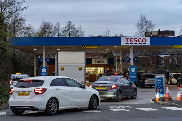 Wigan, İngiltere: 10 Mart 2022: İngiliz sürücüler panik içinde benzin alırken, Tesco benzin istasyonunda benzin almak için kuyrukta bekleyen arabalar