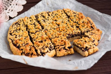 Tahta bir masanın üzerindeki parşömen üzerinde kesilmiş turta. Çörek.