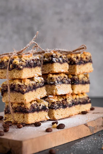Reçelli kurabiyeler düzgünce katlanıp iplikle bağlanır. Kahve çekirdekli gri arka planda kurabiyelerin dikey fotoğrafı..
