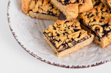 Fırın. Beyaz tabakta reçelli kare kurabiyeler. Sağ üst köşesinde kurabiyeler olan beyaz tabak. Metin için yer