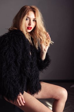 Açık sarı dudaklı, gri arka planda, eko kürklü, kırmızı dudaklı kız..