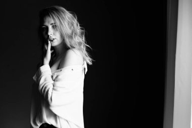 Kız yan duruyor ve baş parmağını dudaklarının yanında tutuyor.