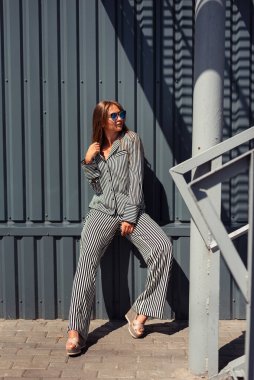 Kafkasyalı kız güneş altında gözlüklü ve çizgili bir takım elbiseyle öylesine oturuyor. Şehir tarzı. Madam başka tarafa bakıyor..