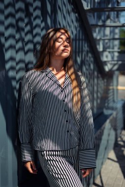 Kafkasyalı kız güneş ışınlarını açık çizgili bir elbiseyle yakalıyor. Pijamalı kız..