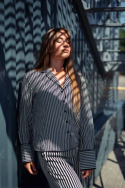 Kafkasyalı kız güneş ışınlarını açık çizgili bir elbiseyle yakalıyor. Pijamalı kız..