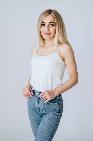 Het Blondje Een Witte Achtergrond Staat Jeans Een Wit Shirt — Stockfoto