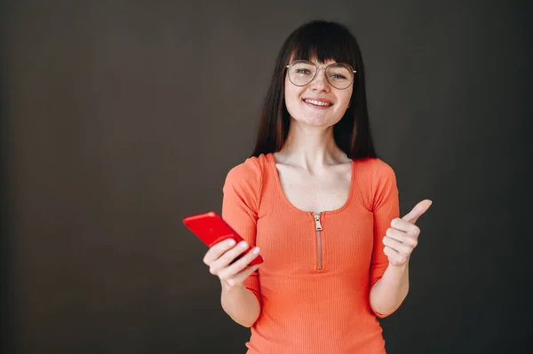 Happy Brunette Dress Glasses Holds Phone Her Hands Shows Thumbs — Φωτογραφία Αρχείου