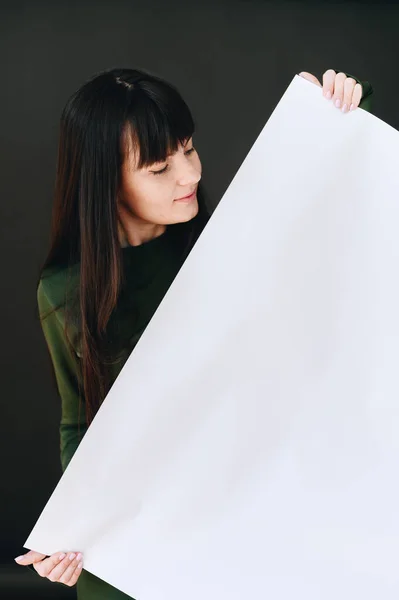 Młoda Dziewczyna Trzyma Rękach Biały Kawałek Papieru Przekątnej Patrzy Niego — Zdjęcie stockowe