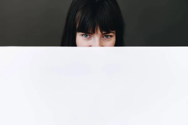 Young Girl Looks Out White Paper Her Eyes Black Background — ストック写真