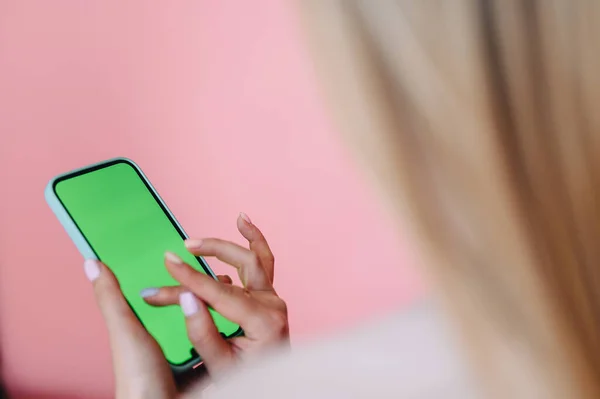 Close-up of a green screen phone and female hands pretend to click on a pink background. Place for application