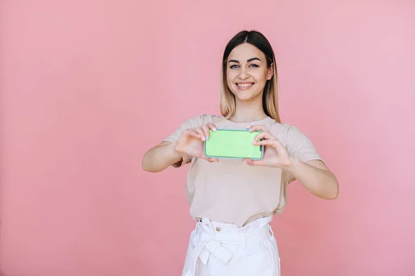 Girl Smile Holds Smart Phone Horizontally Green Screen Pink Background — Φωτογραφία Αρχείου