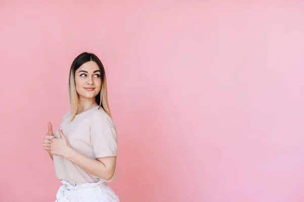 Caucasian Woman Pink Background Gray Shirt Looks Side Raised Hands — Stock fotografie