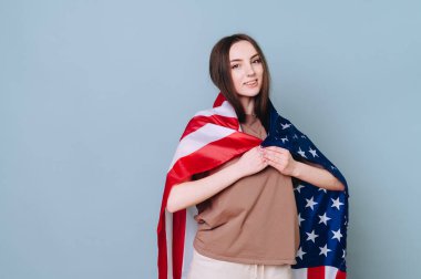 Genç bir esmer gülümsüyor ve omuzlarını mavi bir arka planda Amerikan bayrağıyla örtüyor. Amerika ile Ukrayna