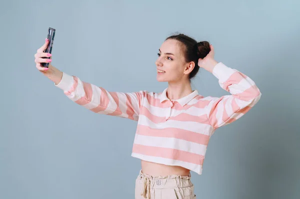 Beautiful Girl Striped Sweater Takes Selfie Blue Background Buns Her — Φωτογραφία Αρχείου