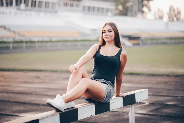 Ένα Νεαρό Κορίτσι Κάθεται Ένα Hurdle Άσπρα Αθλητικά Παπούτσια Στο — Φωτογραφία Αρχείου