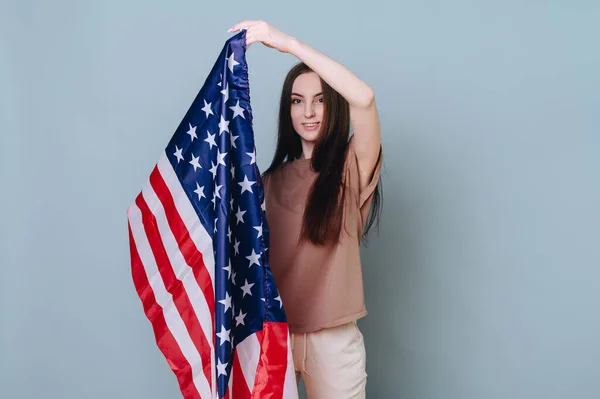Basit giyinmiş genç bir kız arka planda bir Amerikan bayrağını elinde tutuyor. Usa Vatanseverlik Konsepti, Bağımsızlık Günü
