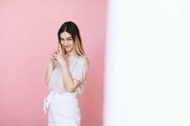 Fotoğrafın yarısı beyaz, diğer yarısı kız ve pembe arka plandaki kameraya neşeyle bakıyor. Metin için boş alan