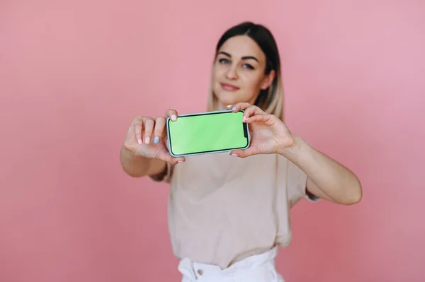 Dívka Drží Horizontálně Chytrý Telefon Zelenou Obrazovkou Růžovém Pozadí Soustředit — Stock fotografie