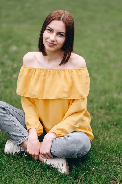 Kare Sarı Bluzlu Bir Kız Yeşil Çimlerin Üzerinde Oturur Gülümser — Stok fotoğraf