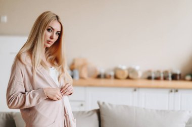 Uzun saçlı, düğmeli elli şık bir adamın yakın plan fotoğrafı. Örgü elbiseli, kameraya bakıyor..