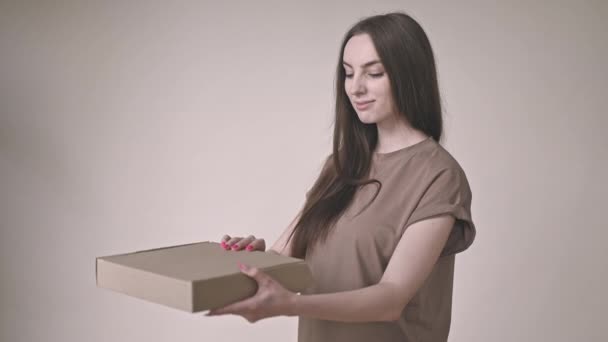 Leende Glad Ung Kvinna Öppnar Kartong Beige Bakgrund Sidovy Försiktigt — Stockvideo