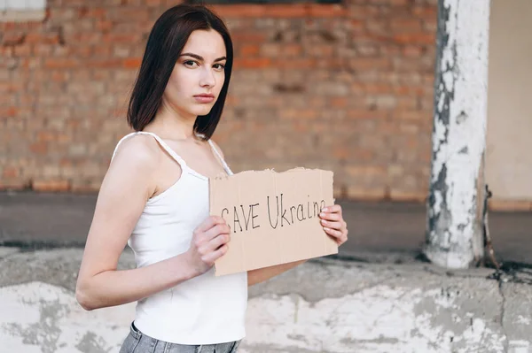 古いレンガ造りの建物の背景に白いTシャツの少女の水平方向の写真 ウクライナを救う — ストック写真