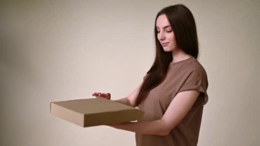 Esmer, yüzünde bir gülümsemeyle kutuyu yakından açmayı başaramadı. Destansı. Monokromda bej bir arkaplanda.