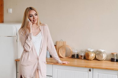 Kız telefonda konuşuyor, mutfaktan dışarı bakıyor. Ev hanımı mutfaktaki masanın yanında duruyor. Isınma işlemi. Telefona göre yemek sipariş etme kavramı