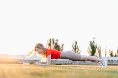 Sunset Stadyumu 'nda Plank Yapan Spor Kızı. Abs dışarıda egzersiz yapıyor. Doğada Arka Işık ve Spor Kızı