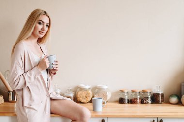 Bir teyze elinde fincanla Tahta Masa 'ya oturur. Kadın Yeni Gün Beklentisinde. Güne bir bardak suyla başlıyoruz. Sağlıklı Yaşam Tarzı Konsepti.