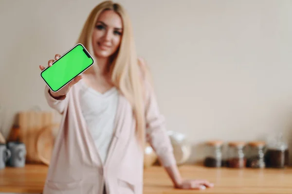 Νεαρή Γυναίκα Δείχνει Πράσινο Τηλέφωνο Οθόνη Στέκεται Στην Κουζίνα Γυναίκα — Φωτογραφία Αρχείου