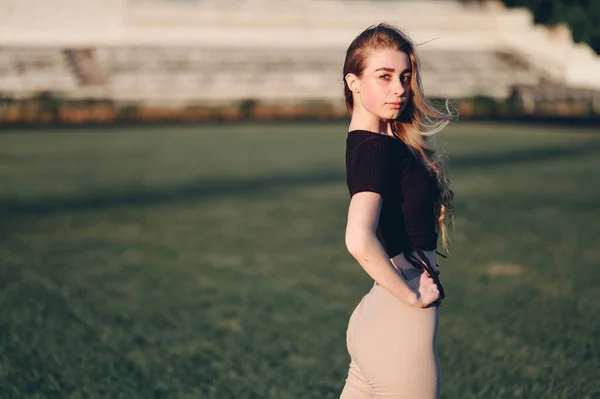 Black Top 'taki genç bir kadın, Yeşil Çimlerin Üzerinde Güneş' te duruyor. Fitness Reklam Maratonu Konsepti. Boş Boşluk.