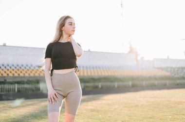 Spor Giyim 'de saçını düzelten kız stadyumun kenarına bakıyor. Antrenmandan sonra kırmızı yanaklı kız