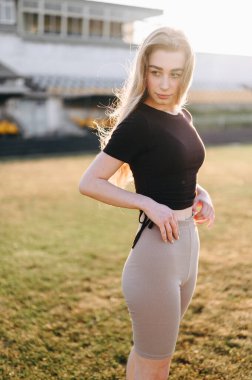 Siyah bluzlu genç kız gün batımında otların üzerinde duruyor ve başka tarafa bakıyor. Bir yaz akşamı bir kadın spor için içeri girer. Sağlıklı bir yaşam tarzı. Çenede çukur