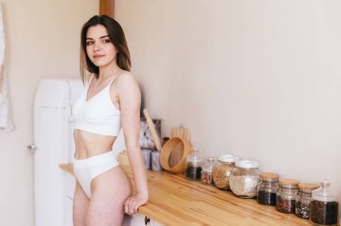 Açık Mutfakta İç Çamaşırlı Genç Bir Kadın Var. Evde güzel bir sabah. Sağlıklı ve bakımlı atletik vücut.