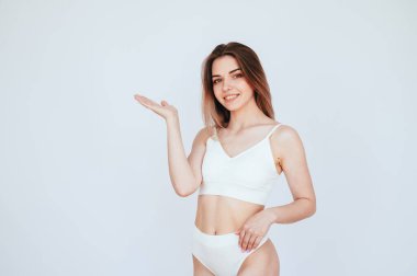 Güzel kadın vücudu. Kız elini beyaz iç çamaşırlı boşluğa doğrultuyor. Vücut bakımı ve kadın sağlığı kavramı. reklam afişi