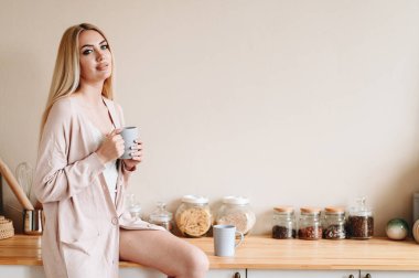 Kafkasyalı kadın elinde bardakla masada oturuyor. Güzel günaydın.