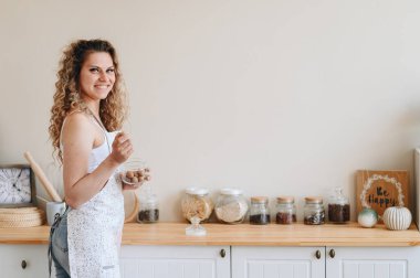 Mutfakta Önlüklü Kıvırcık Kadın Kahvaltı Hazırlıyor. Hafif İç Mutfak. Güne harika bir başlangıç, günaydın. Mutfak Günlüğü Konsepti