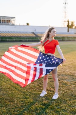 Amerikan Bayraklı Bir Kızın Tam Uzun Dikey Fotoğrafı. Anma Günü Spor Kızı. Altın Saat 'te gün batımı.