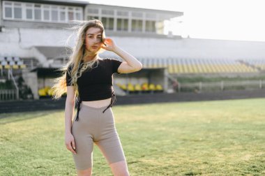 Rüzgâr, Spor Giyim 'deki Uzun Saçlı Kız' ı geliştiriyor. Genç kadın spor için stadyuma geldi. Kurşun Sağlıklı ve Aktif Yaşam Tarzı.