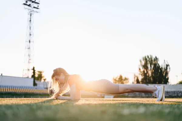 Spor Konsepti Kırmızılı Genç Kadın Çimlerde Plank Yapıyor Yaz Gecesi — Stok fotoğraf