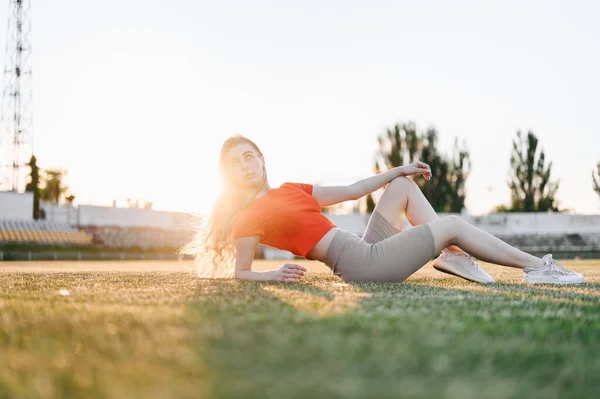 Спортивная Концепция Молодая Женщина Красном Лежит Траве Оглядывается Через Плечо — стоковое фото